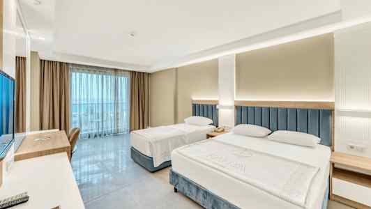 Hotellrum med två sängar, skrivbord och utsikt mot balkong. (AI-genererad text)