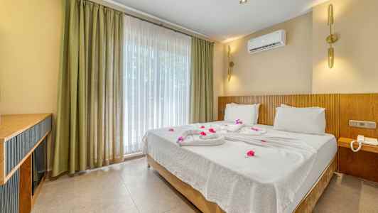 Hotellrum med en dubbelsäng bäddad med vita lakan och dekorerad med blommor. (AI-genererad text)