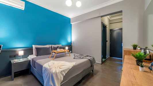 Sovrum med en dubbelsäng, ett brickbord, blå vägg och inredning. (AI-genererad text)