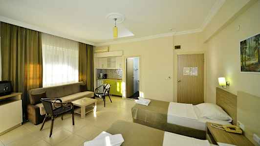 Ett hotellrum med två enkelsängar, en soffa, ett soffbord och ett litet kök. (AI-genererad text)