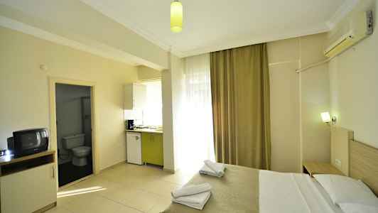 Ett hotellrum med en säng, köksdel och ingång till badrum. (AI-genererad text)