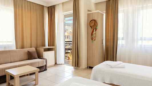 Ett hotellrum med två sängar, en soffa och balkongdörr. (AI-genererad text)