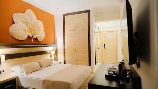 Ett hotellrum med en säng, garderob och orange väggdekoration. (AI-genererad text)