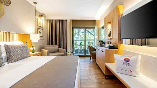 Ett hotellrum med en bekväm säng, en fåtölj, en sittgrupp vid balkongen och moderna möbler. (AI-genererad text)