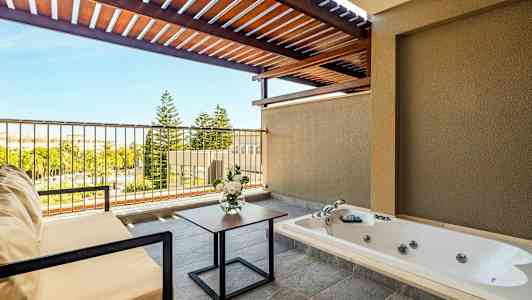 En terrass med jacuzzi, sittmöbler, blombukett och utsikt över grönska. (AI-genererad text)