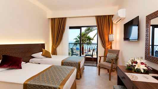 Hotellrum med två enkelsängar, fönster med utsikt mot palmer och hav. (AI-genererad text)