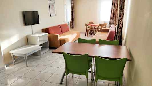 Ett vardagsrum med soffor, ett matbord med stolar och en väggmonterad tv. (AI-genererad text)