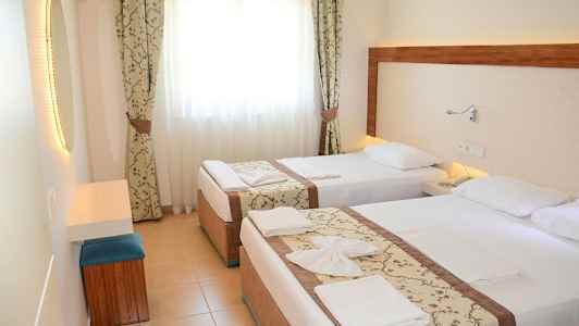 Hotellrum med två enkelsängar, ljusa gardiner och en spegel. (AI-genererad text)