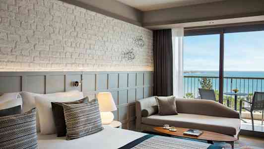 Bild av ett modernt hotellrum med havsutsikt från en balkong. (AI-genererad text)