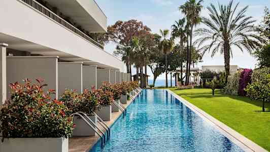 Lång pool med omgivande grönska och moderna byggnader. (AI-genererad text)