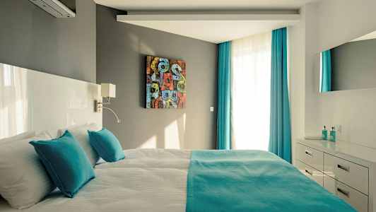 Modernt sovrum med dubbelsäng, turkosa detaljer och ljusa möbler. (AI-genererad text)