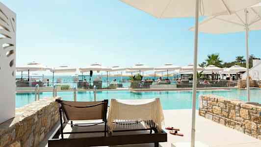 Solstolar vid en utomhuspool med parasoller och utsikt över havet. (AI-genererad text)