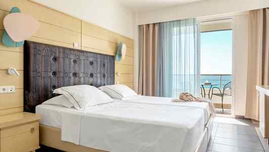 Hotellrum med bäddad dubbelsäng, modern inredning och balkong med utsikt över havet. (AI-genererad text)