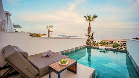 Utsikt över en liten pool med solstol och bord, omgiven av palmer. (AI-genererad text)