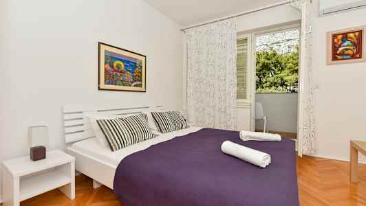 Ett sovrum med en dubbelsäng, lila överkast och två viktade handdukar. (AI-genererad text)