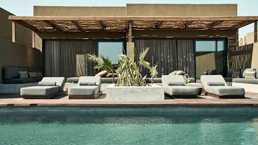 Bild av en pool framför en uteplats med solstolar och soffgrupp. (AI-genererad text)