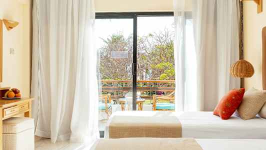 Ett hotellrum med dubbelsängar och en glasdörr som leder ut till en balkong. (AI-genererad text)