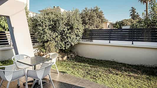 En uteplats med ett bord och fyra stolar, omgiven av grönska och staket. (AI-genererad text)