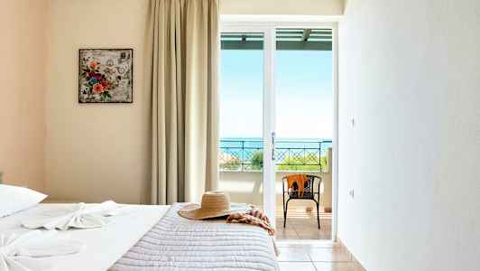 Ett hotellrum med en säng, en hatt och ett fönster med utsikt mot havet. (AI-genererad text)