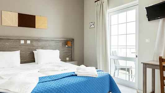 Ett hotellrum med en dubbelsäng, blå överkast och vita sängkläder. (AI-genererad text)