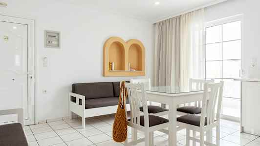 En ljus inomhusmiljö med vita möbler, ett grått soffset och beige detaljer på väggen. (AI-genererad text)