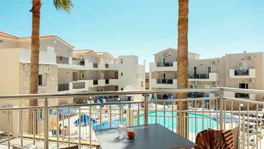 Hotellbyggnad med balkonger och pool, sett från en terrass. (AI-genererad text)