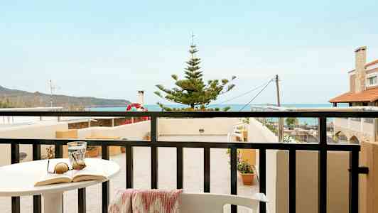 En balkong med utsikt mot havet och närliggande byggnader. (AI-genererad text)