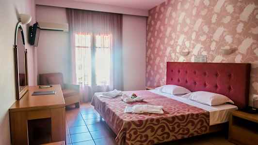 Ett hotellrum med en dubbelsäng, skrivbord, fåtölj och dekorerad vägg. (AI-genererad text)