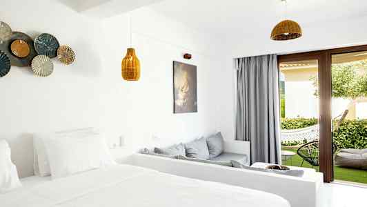 Ett hotellrum med ljus inredning och öppning mot en terrass med grönska. (AI-genererad text)