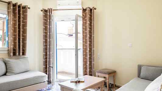 Bild av ett ljust vardagsrum med två soffor, ett soffbord och gardiner framför en balkongdörr. (AI-genererad text)