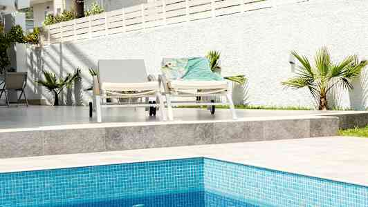 Två solstolar vid en pool med vit bakgrundsgräns. (AI-genererad text)