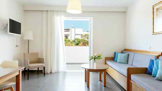 Ett ljust vardagsrum med en soffa, bord och stolar, samt en öppning mot balkongen. (AI-genererad text)