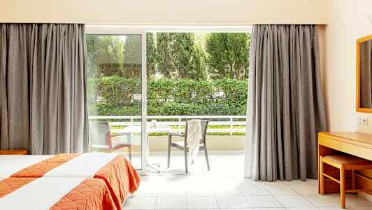 Hotellrum med två enkelsängar och stor fönsterdörr som leder ut till en balkong. (AI-genererad text)