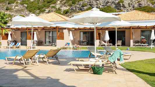 Solstolar vid en pool framför bungalows med trädgård. (AI-genererad text)