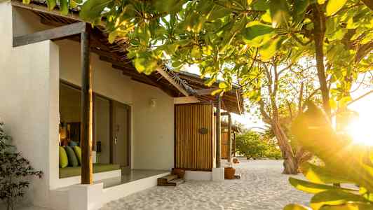 Bungalower på stranden omgivna av grönska och belysta av solsken. (AI-genererad text)