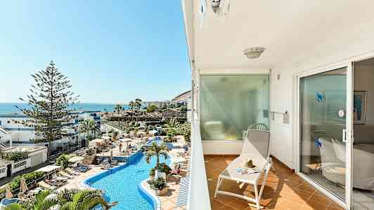 Balkong med solstol och utsikt över poolområde och hav. (AI-genererad text)