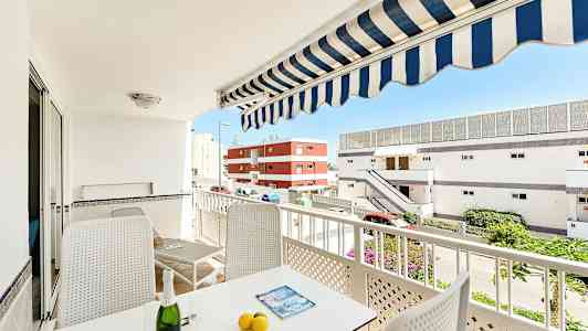 En balkong med möblemang, parasoll och utsikt mot byggnader. (AI-genererad text)