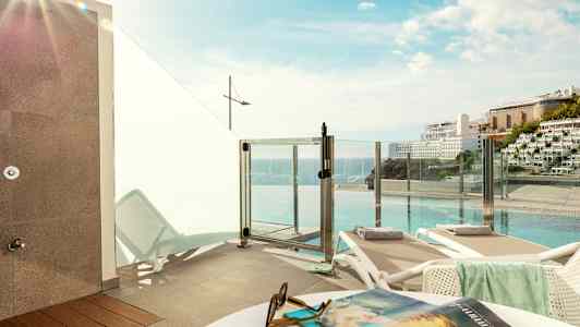 Bild av en solterrass med solstolar och utsikt över pool och hav. (AI-genererad text)