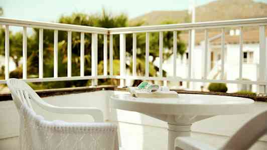 Ett trädäck med stolar och ett bord, omgiven av räcken. (AI-genererad text)