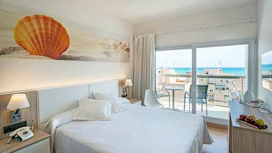 Ett hotellrum med en dubbelsäng, dekorativ konst av en orange snäcka på väggen och en altan med havsutsikt. (AI-genererad text)