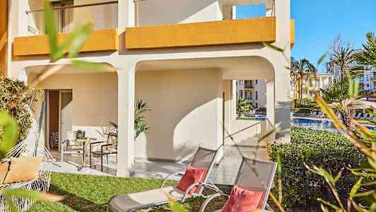 Uteplats med gräsmatta, solstolar och parasoll vid ett hotell. (AI-genererad text)