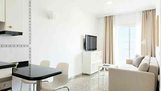 Ett ljust vardagsrum med en soffa, bord, TV och matplats. (AI-genererad text)