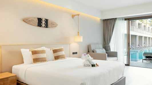 Hotellrum med säng, fåtölj, och utsikt över pool från en glasdörr. (AI-genererad text)