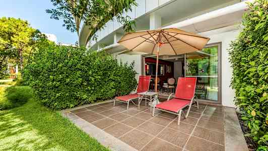 En uteplats med två röda solstolar, ett parasoll och grönska omkring. (AI-genererad text)