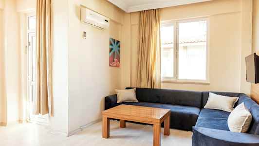 Ett vardagsrum med blå soffa, träbord och två fönster. (AI-genererad text)