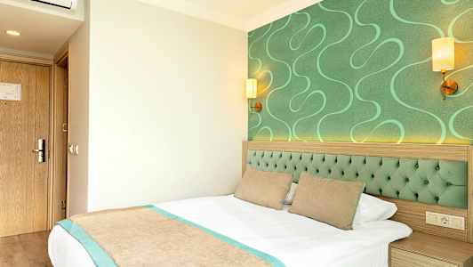 Hotellrum med gröna detaljer och en säng. (AI-genererad text)