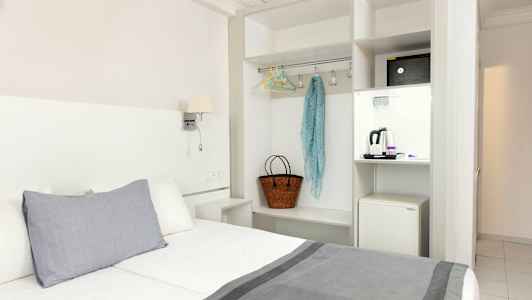 Hotellrum med säng, garderob och en minikyl. (AI-genererad text)