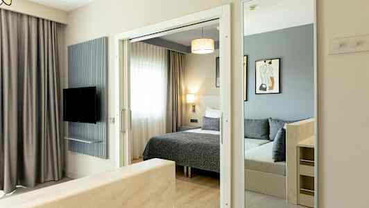 Bild av ett hotellrum med säng, spegel och TV. (AI-genererad text)