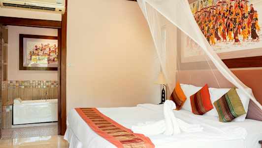 Sovrum med dekorativ myggnät över en dubbelsäng, färgglada kuddar och konst på väggarna. (AI-genererad text)