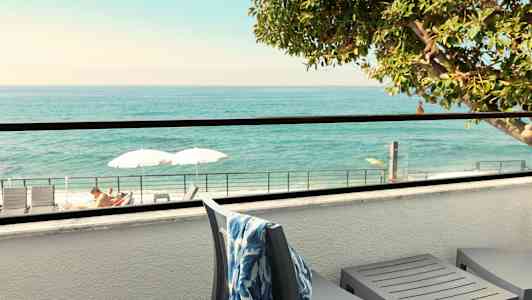 Terrass med utsikt över havet, solstolar och parasoller synliga. (AI-genererad text)